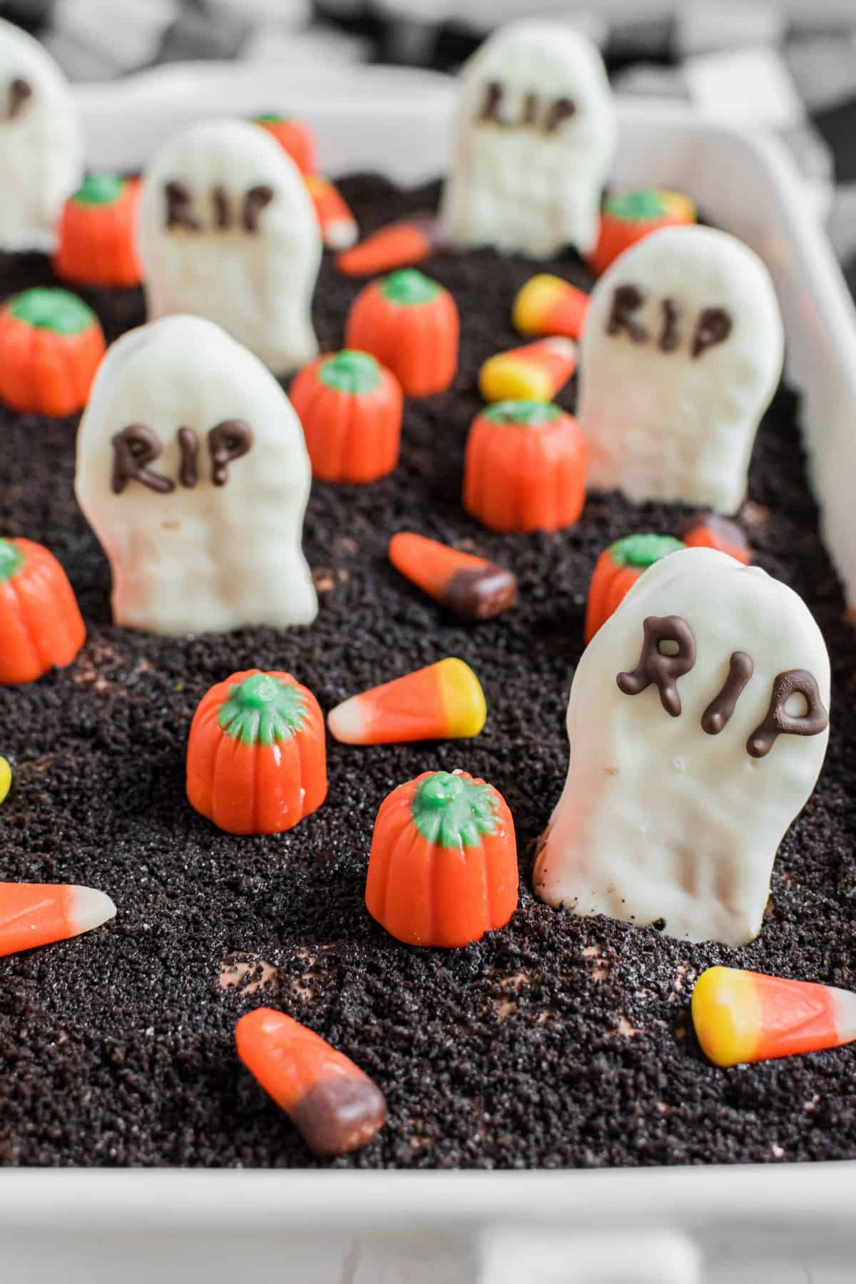 Close up of oreo topped dirt cake with tombstones and pumpkins.