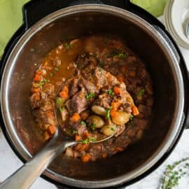 Beef bourguignon in the instant pot being lifted with a ladle.