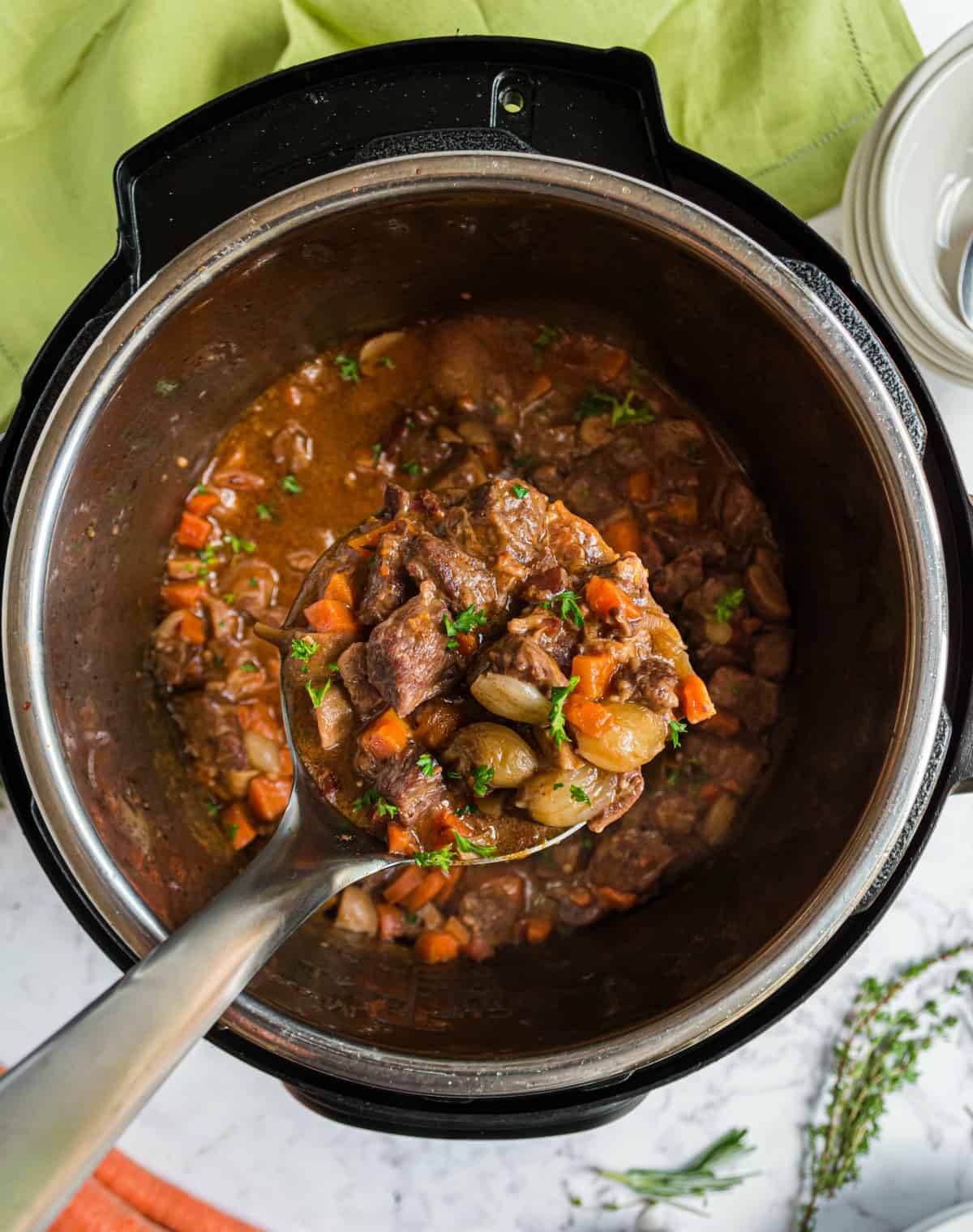 Beef bourguignon in the instant pot being lifted with a ladle.