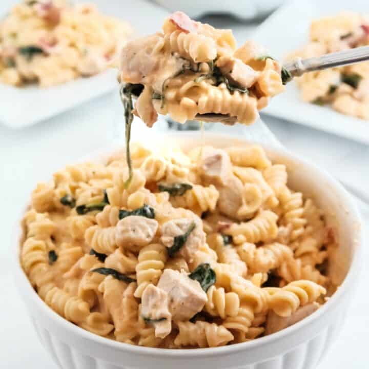 Large scoop of crack chicken pasta being lifted out of a bowl.