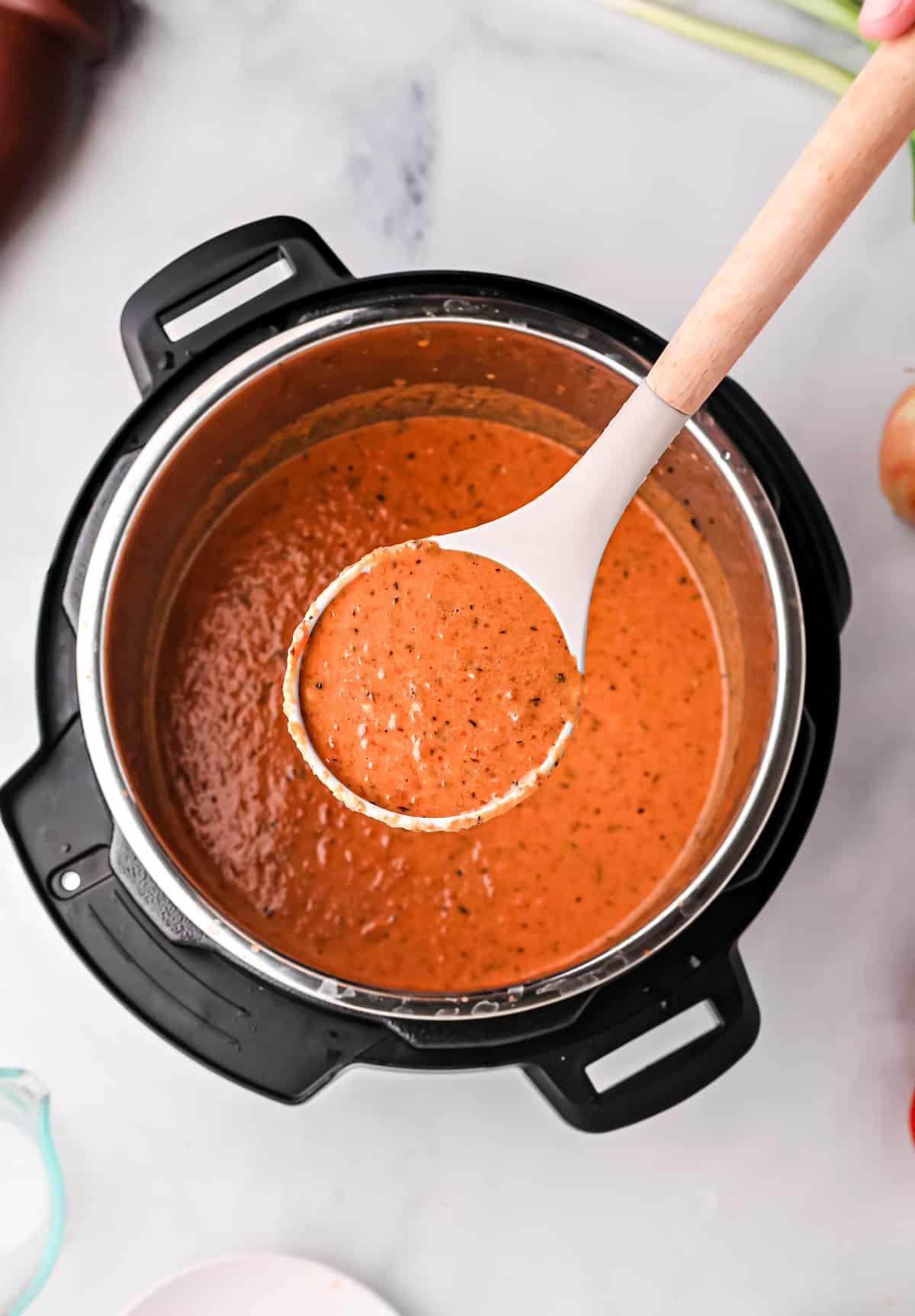 Tomato soup being ladled out of the Instant Pot.