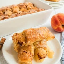 Peach dumplings served stacked on a white dessert plate.