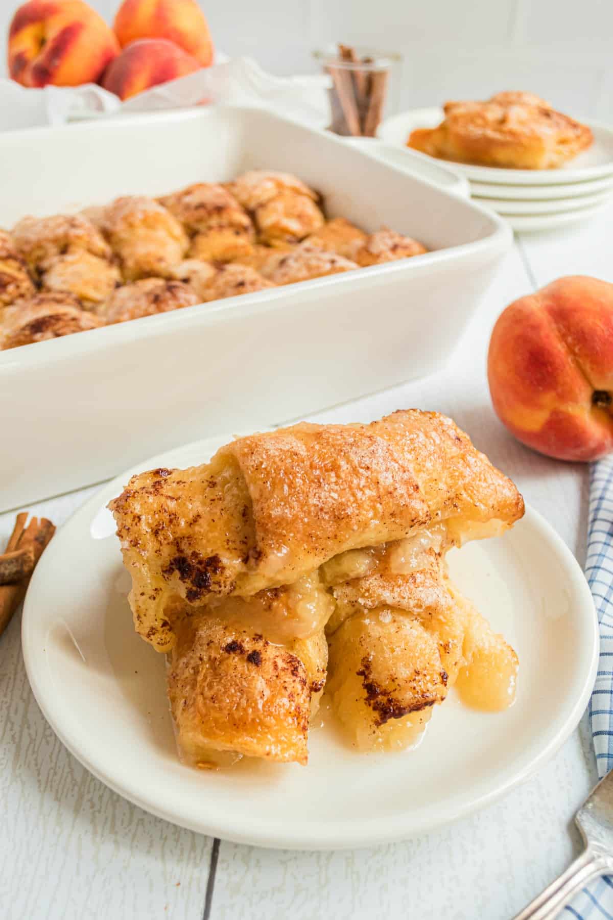 Peach dumplings served stacked on a white dessert plate.