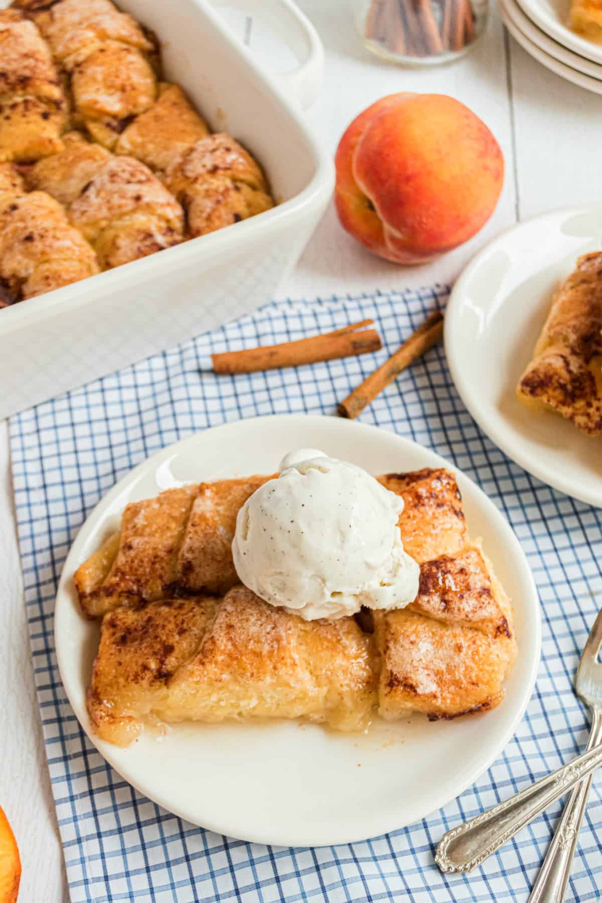 Peach Dumplings on a white plate with vanilla ice cream.