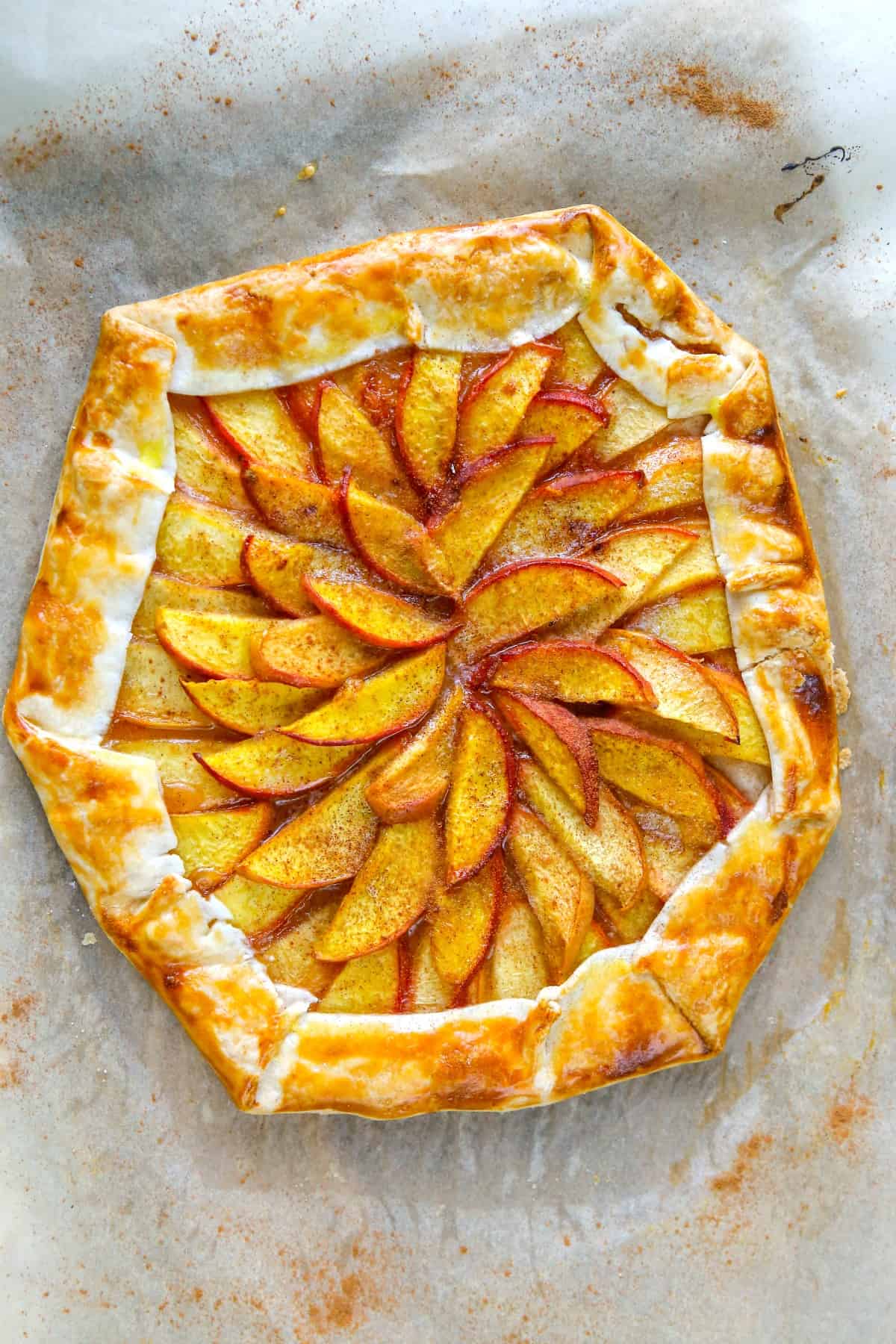 Rustic galette with peaches on parchment paper.