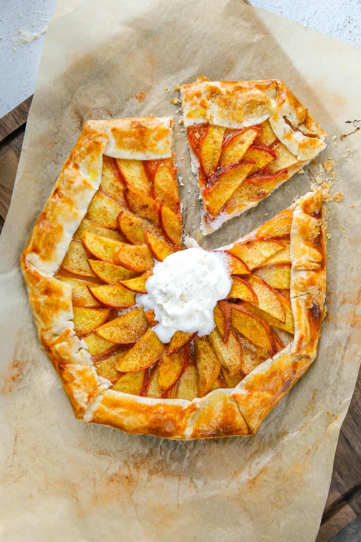 Peach galette with one slice cut and topped with ice cream.