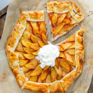 Peach galette with scoop of vanilla ice cream and one slice cut.