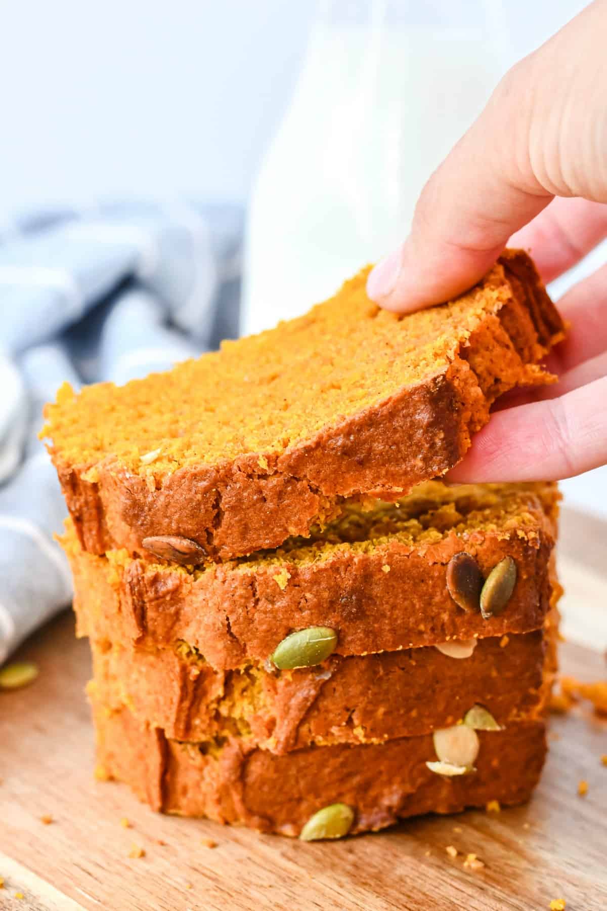 Stack of sliced pumpkin bread with one piece being lifted off stack.