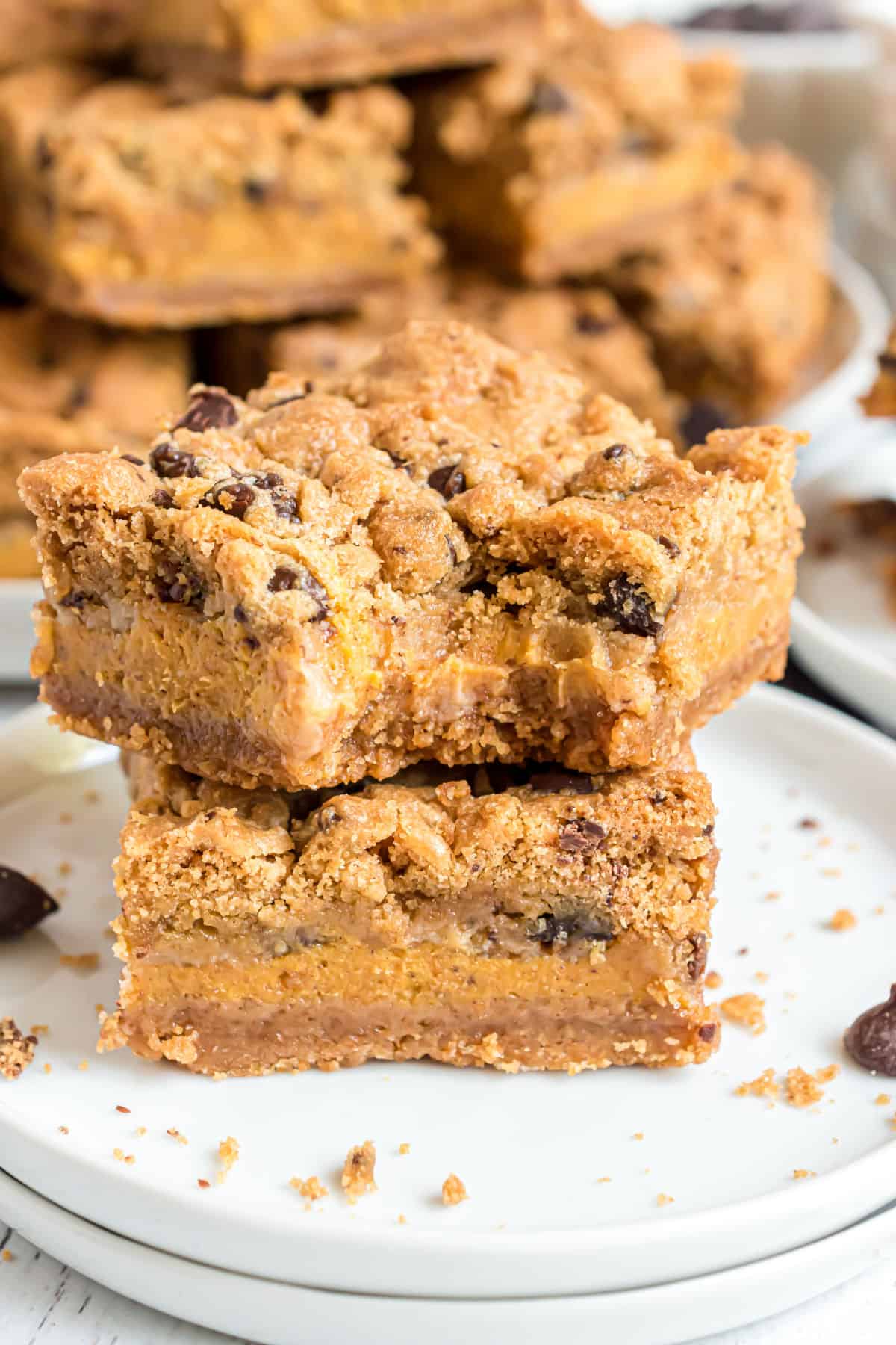 Stack of two pumpkin chocolate chip cheesecake bars, with a bite taken out of the top bar.