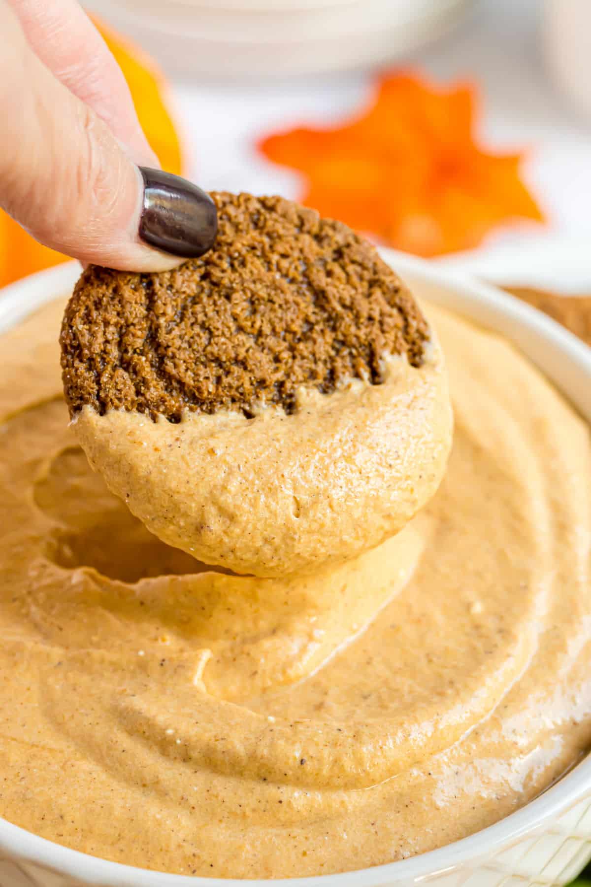 Pumpkin dip with a gingersnap being dunked in the dip.