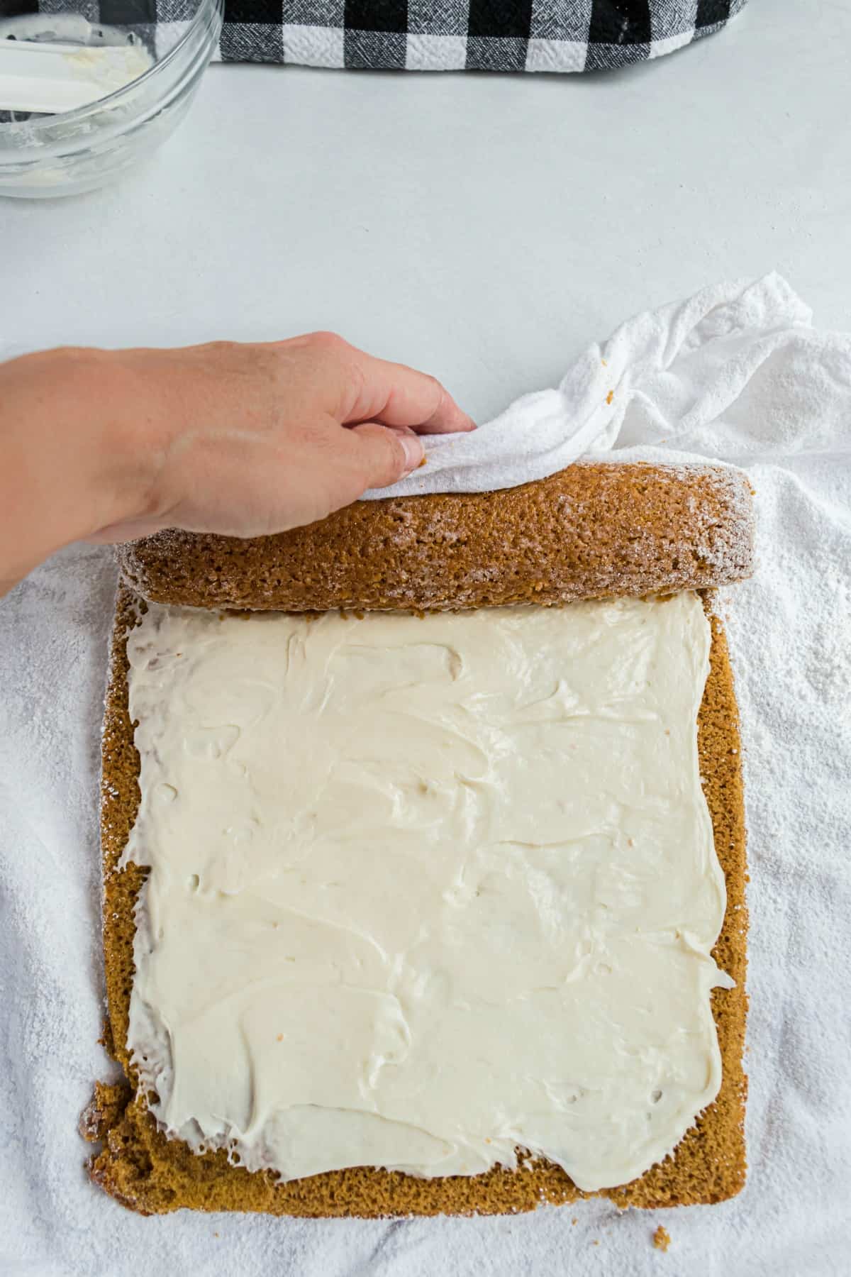 Re-rolling a pumpkin cake roll filled with cream cheese frosting.