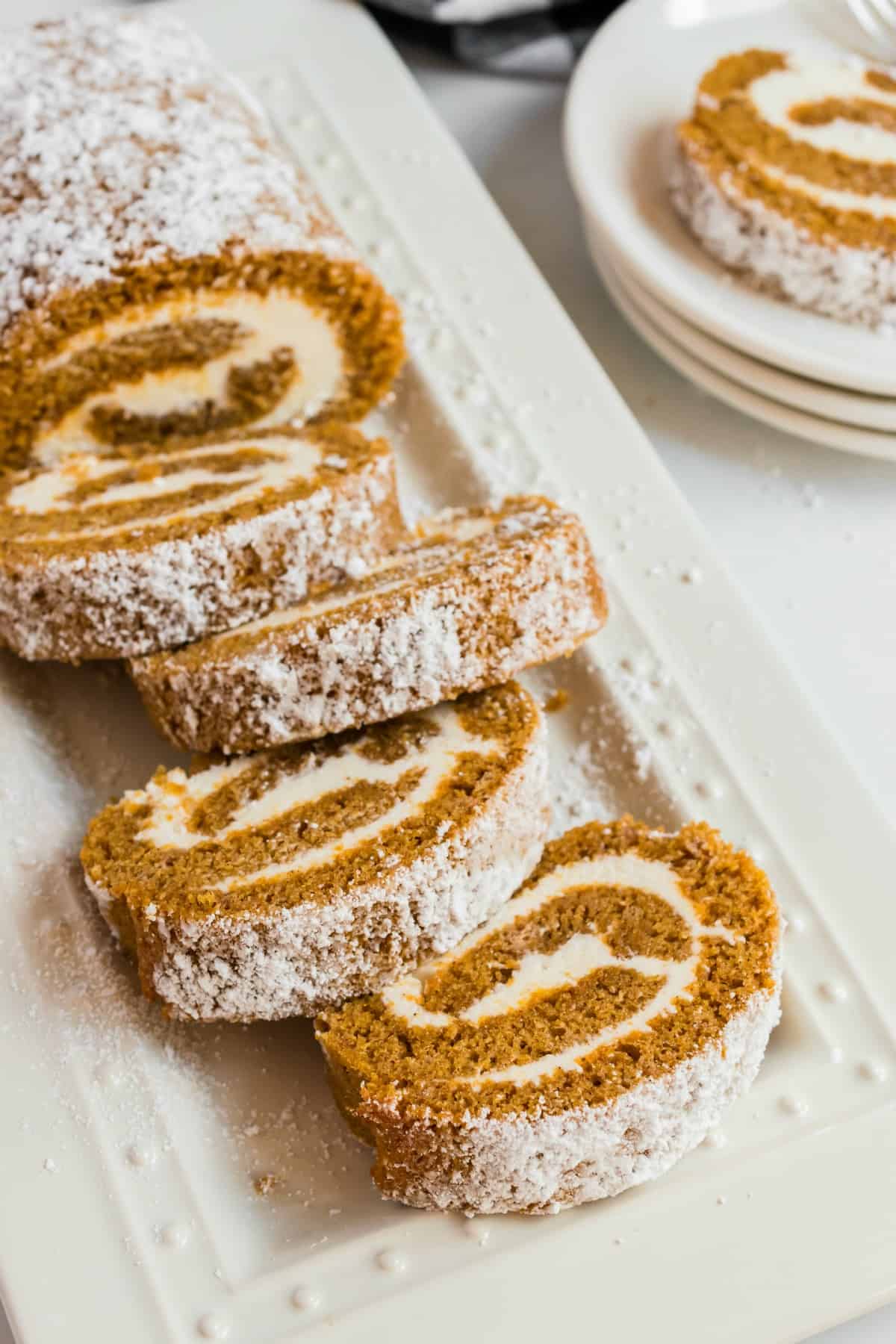 Sliced pumpkin roll on a white serving platter.