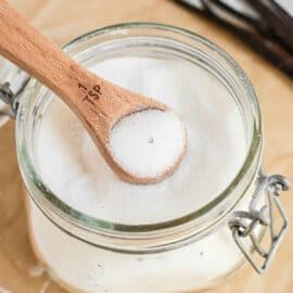 Homemade vanilla sugar in a mason jar with teaspoon scoop.