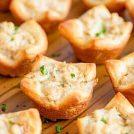 Warm crab puffs on a wooden serving tray.