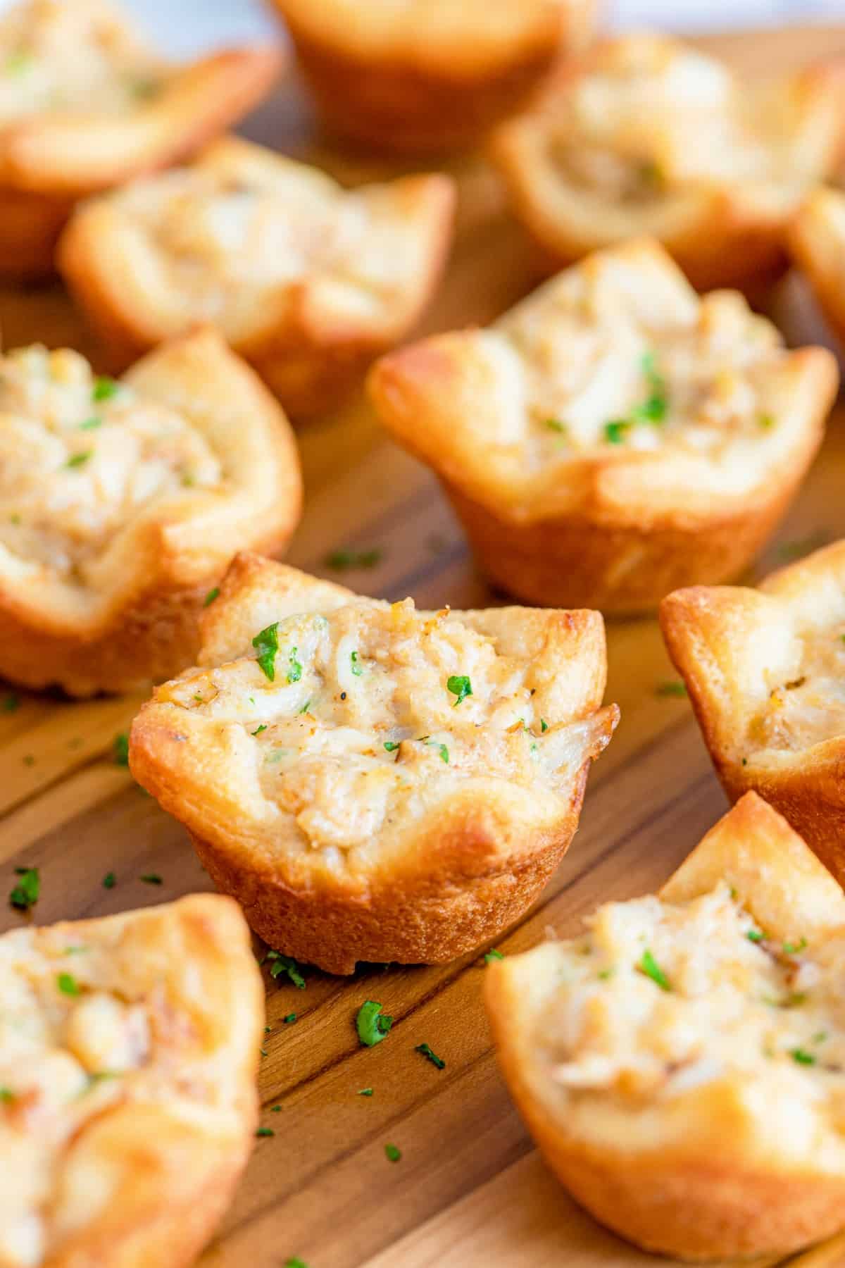 Warm crab puffs on a wooden serving tray.