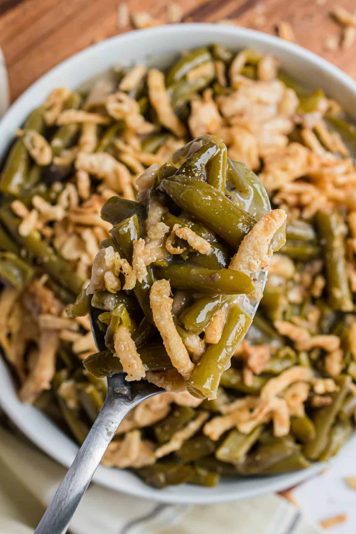 Serving dish with green bean casserole and french fried onions.