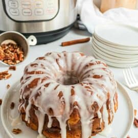 Cinnamon roll bread on a white serving plate with instant pot in background.