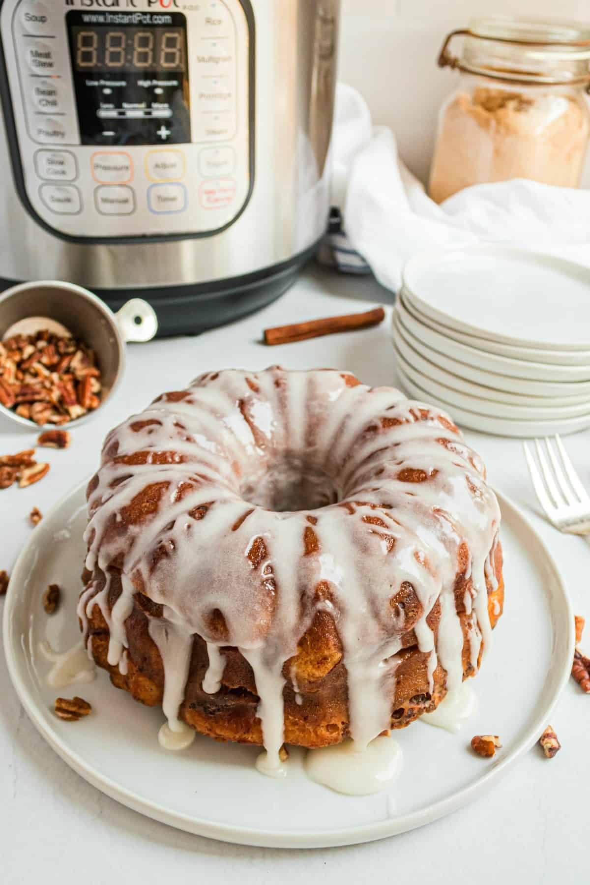 Cinnamon roll bread on a white serving plate with instant pot in background.