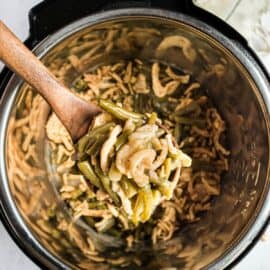 Instant pot green bean casserole being lifted by wooden spoon.