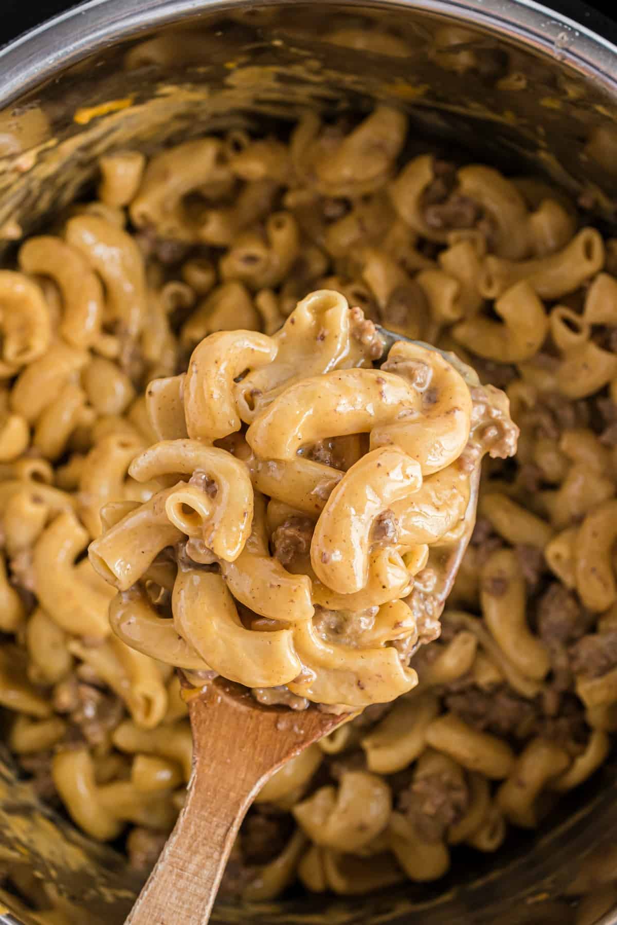 Hamburger helper in the pressure cooker with wooden spoon.