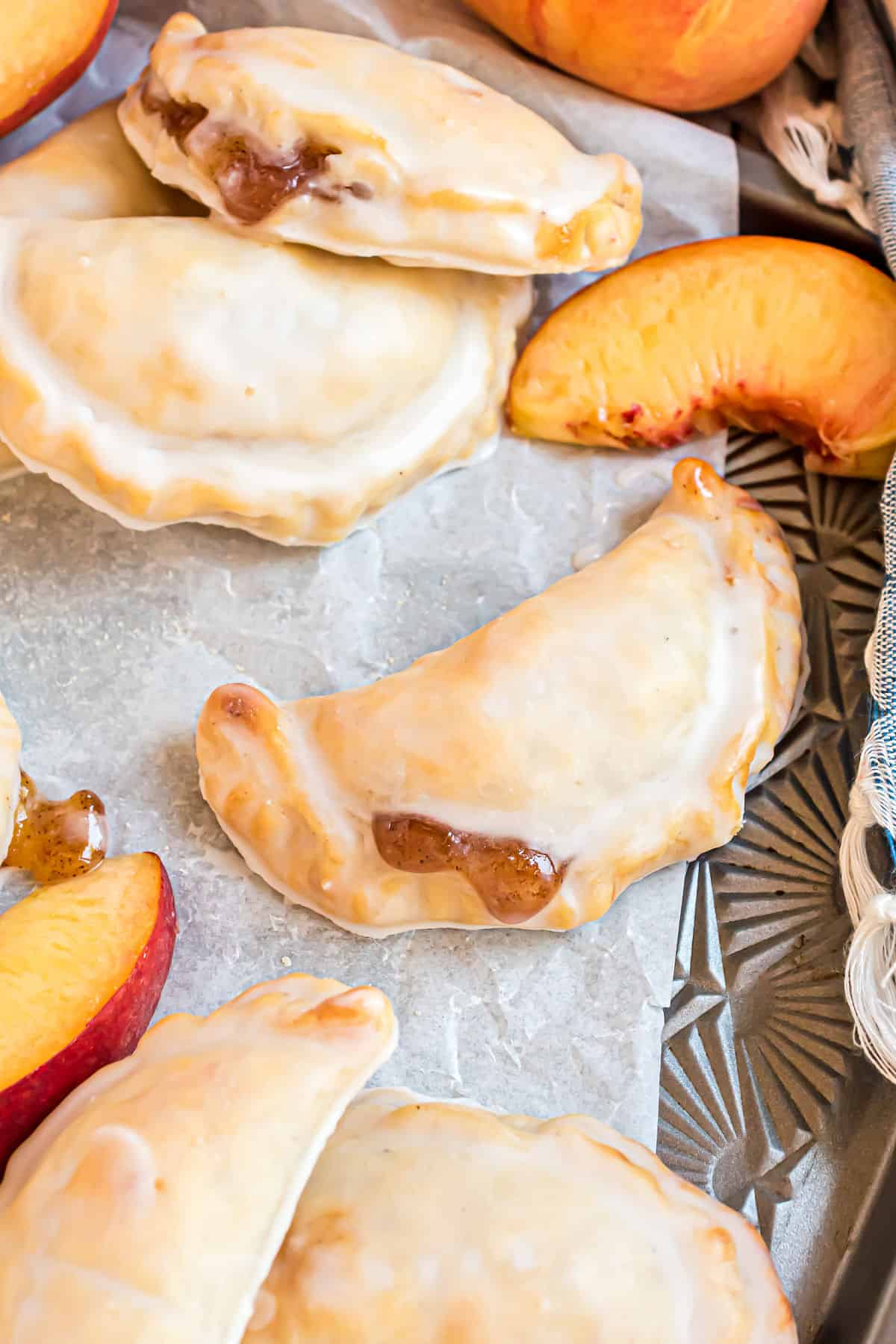 Peach hand pies on parchment paper lined baking sheet.