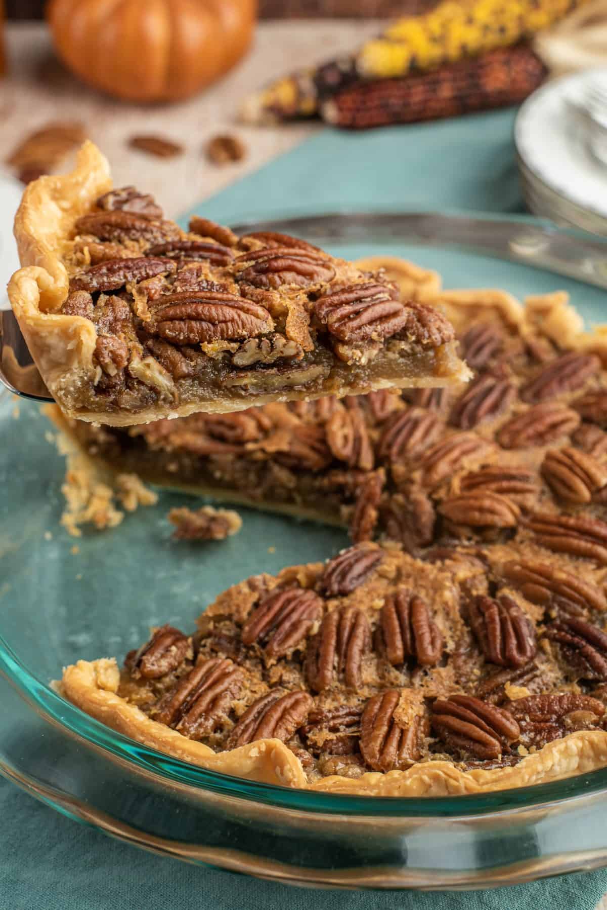 Pecan pie slice being lifted out of pie with spatula.