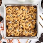 Spooky brookies: A brownie topped with cookie dough, chocolate chips, and candy eyes in a square baking pan.