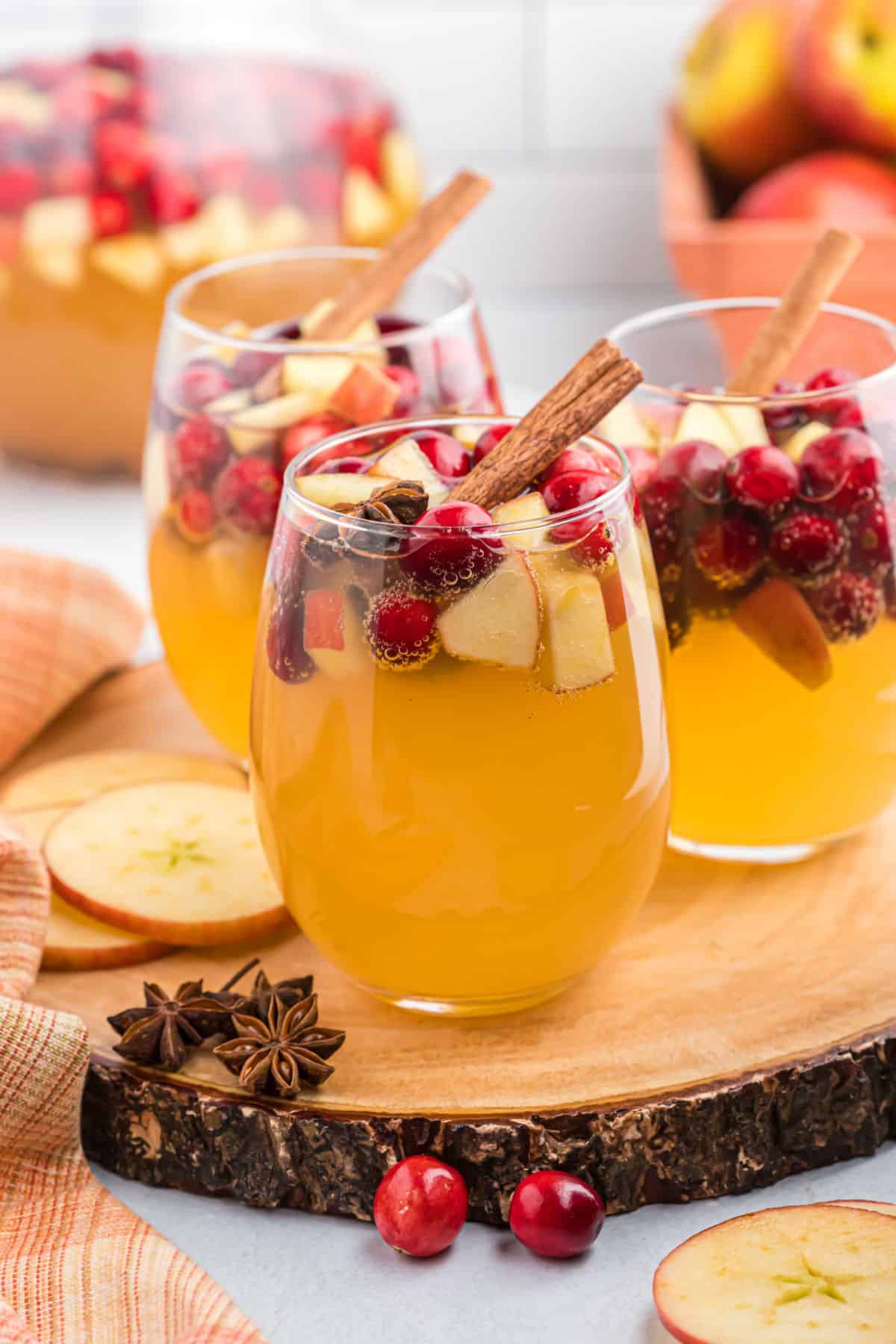 Apple sangria in a wine glass with apples and cranberries.