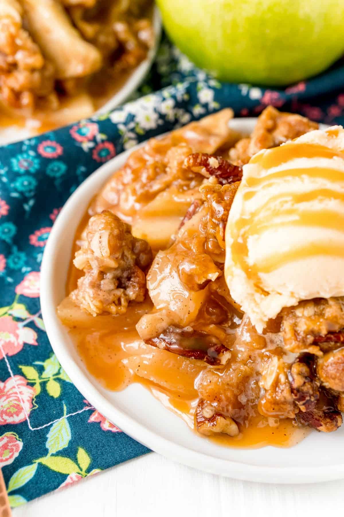 Apple crisp on plate with ice cream and caramel.