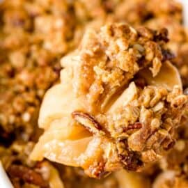 Apple crisp in a baking dish with a scoop lifted out.