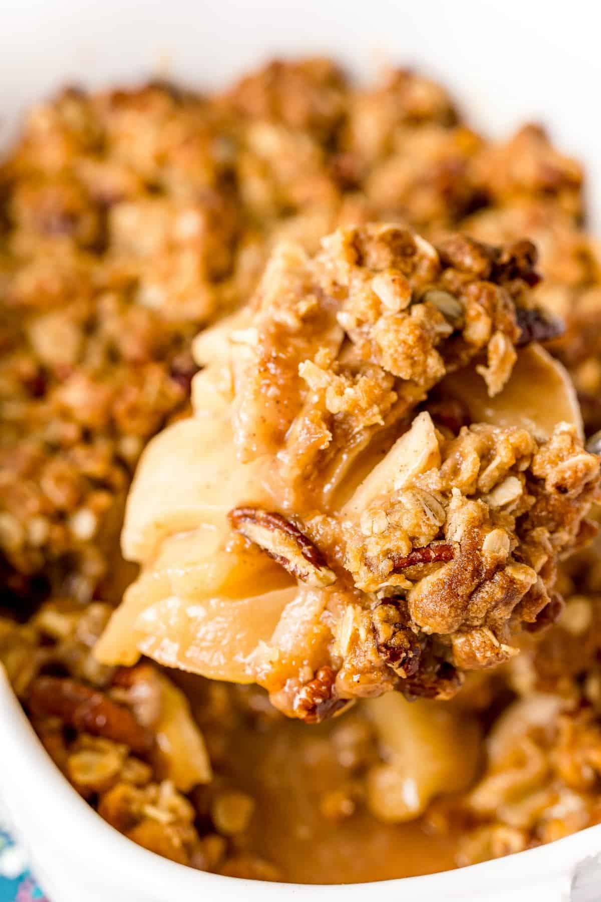 Apple crisp in a baking dish with a scoop lifted out.