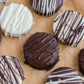 Chocolate and white chocolate covered oreos on parchment paper.
