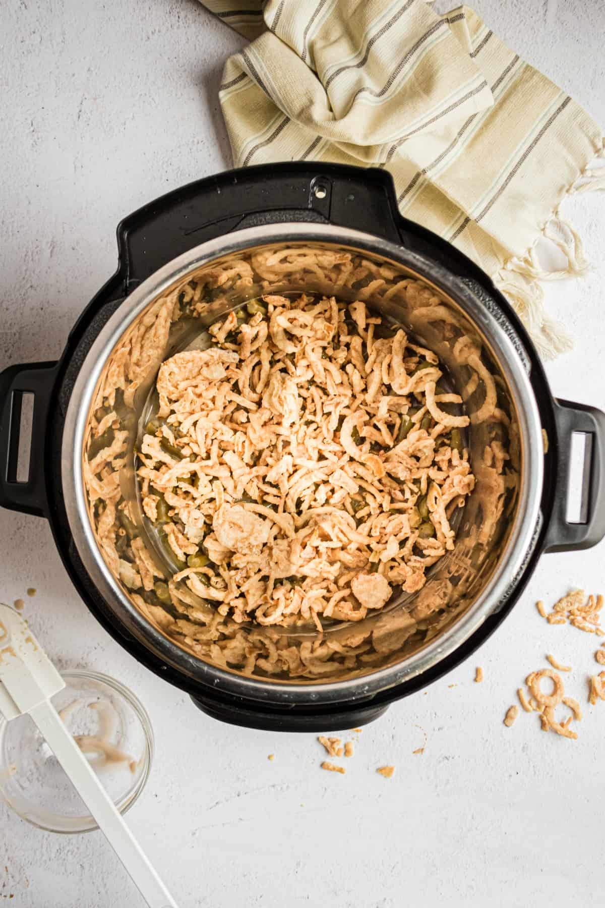 Green bean casserole in the pressure cooker topped with crispy fried onions.