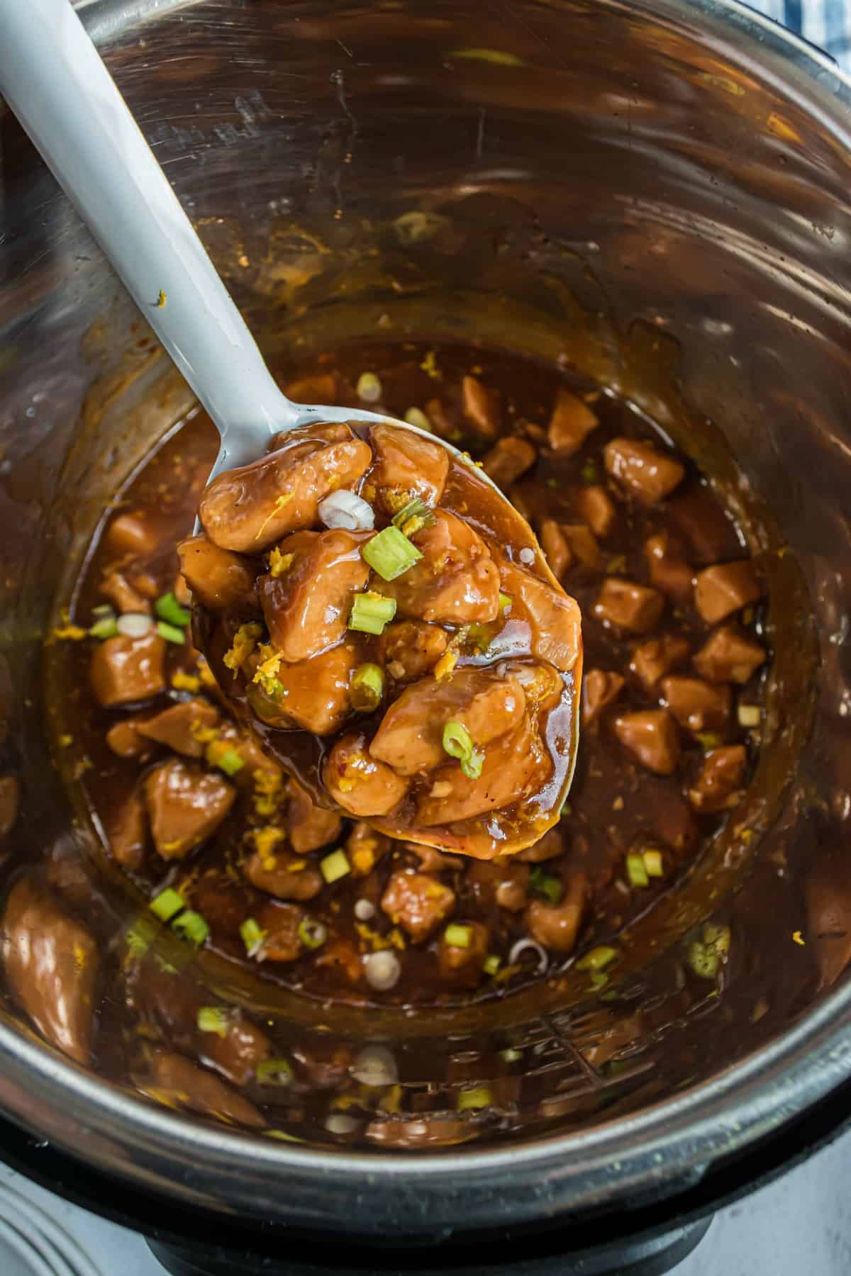 Orange chicken ladled out of Instant Pot.