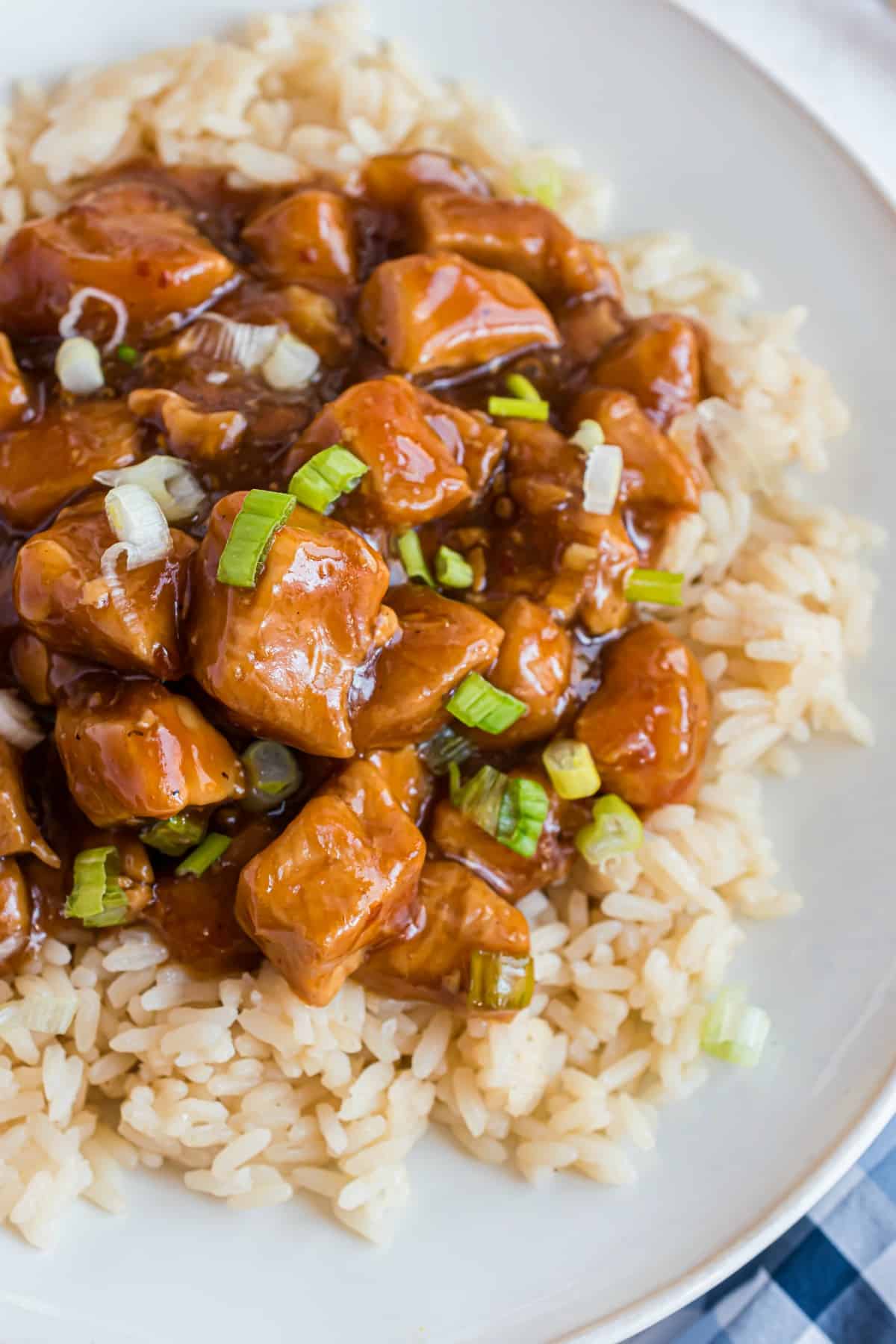 Brown rice with orange chicken on a white plate.