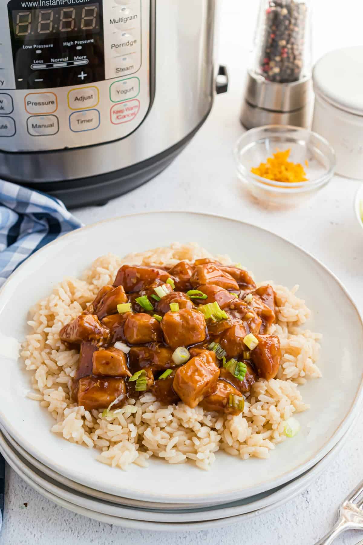 Orange chicken on rice served on a white plate.