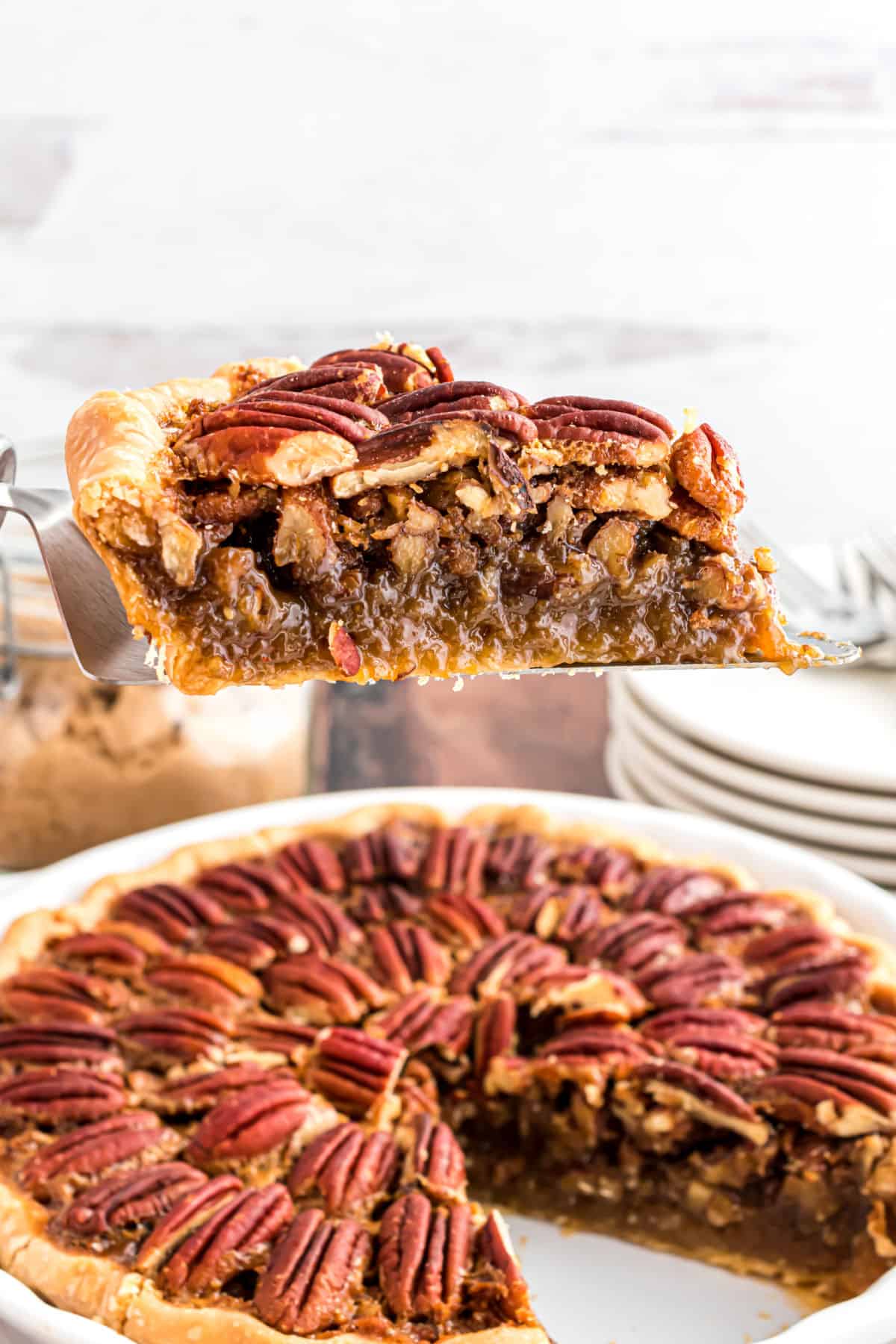 Slice of pecan pie being lifted out of pie plate with a spatula.