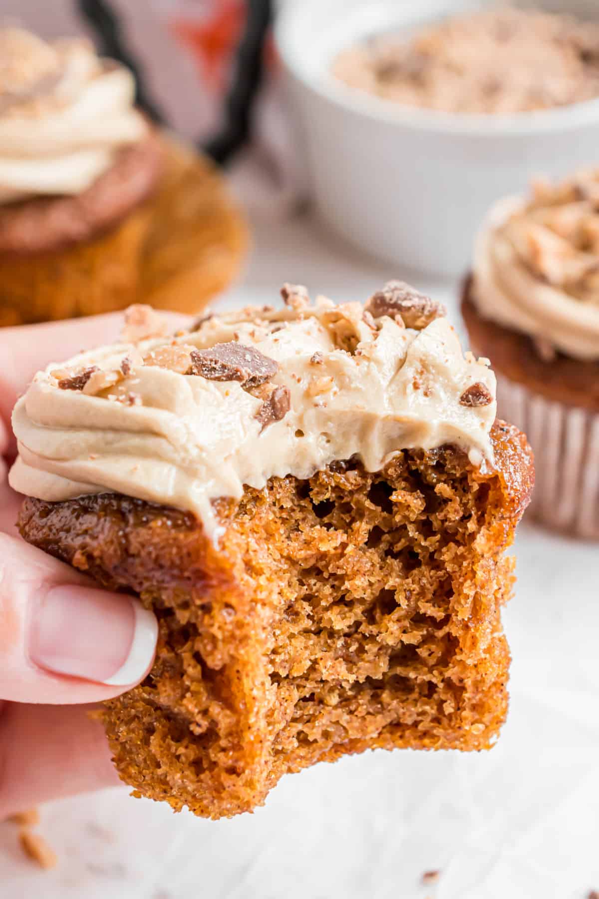 Maple frosted pumpkin cupcake with one bite removed.