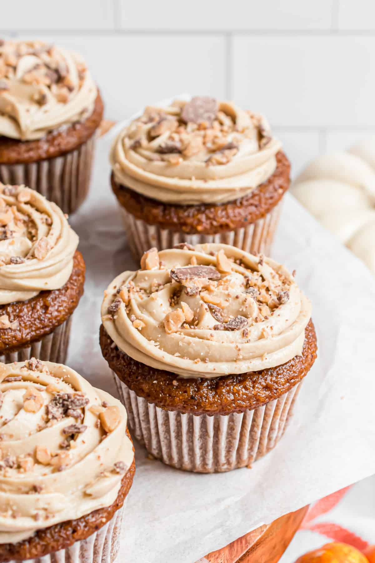 Pumpkin cupcakes on white cake platter to serve.