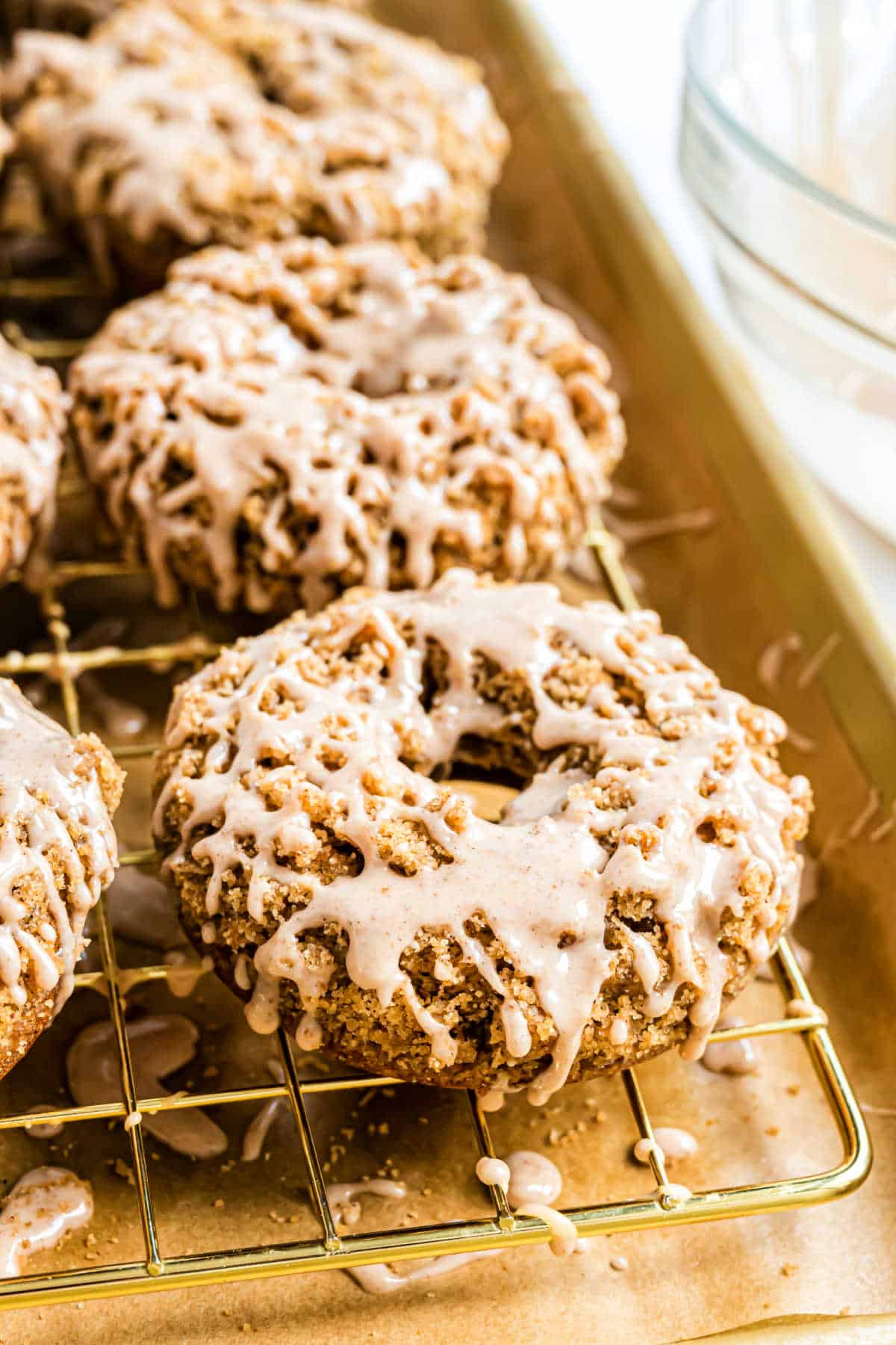 Close-up of pumpkin streusel donuts with crumb topping and white glaze on a cooling rack.