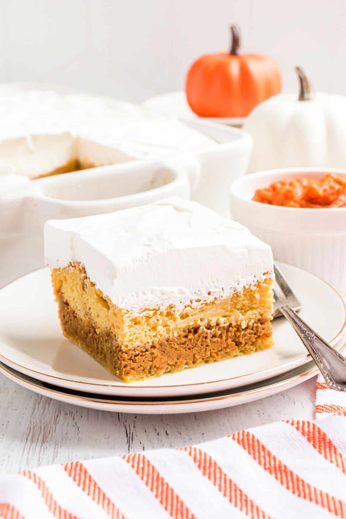 Slice of pumpkin magic cake on a stack of white plates.