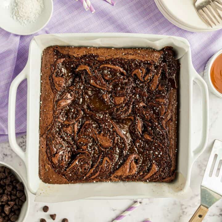 Uncut brownies with caramel swirl in a white baking dish.