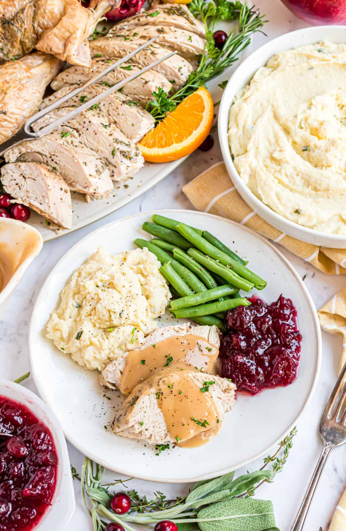 Plate with turkey, mashed potatoes, cranberry sauce, and green beans for thanksgiving dinner.