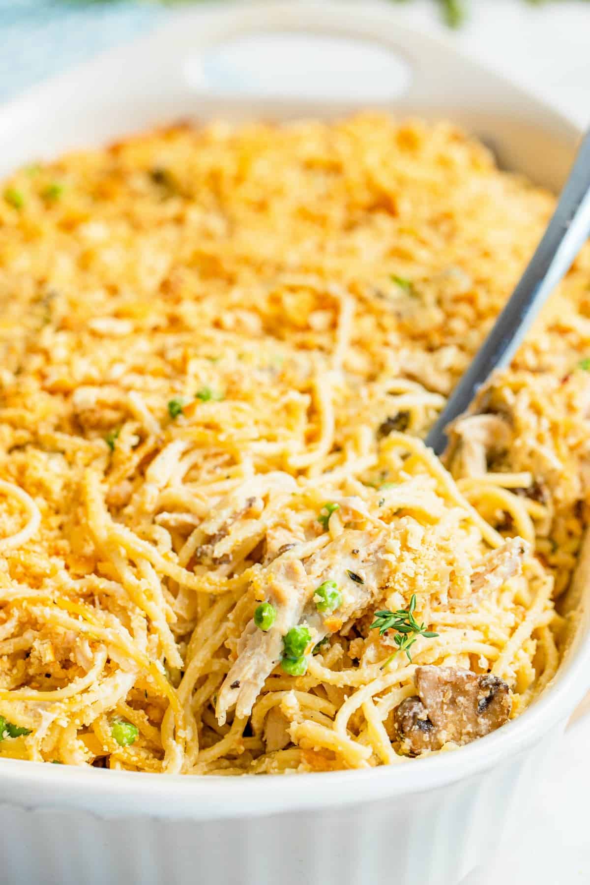Turkey tetrazzini in a bagkin dish with spoon for serving.