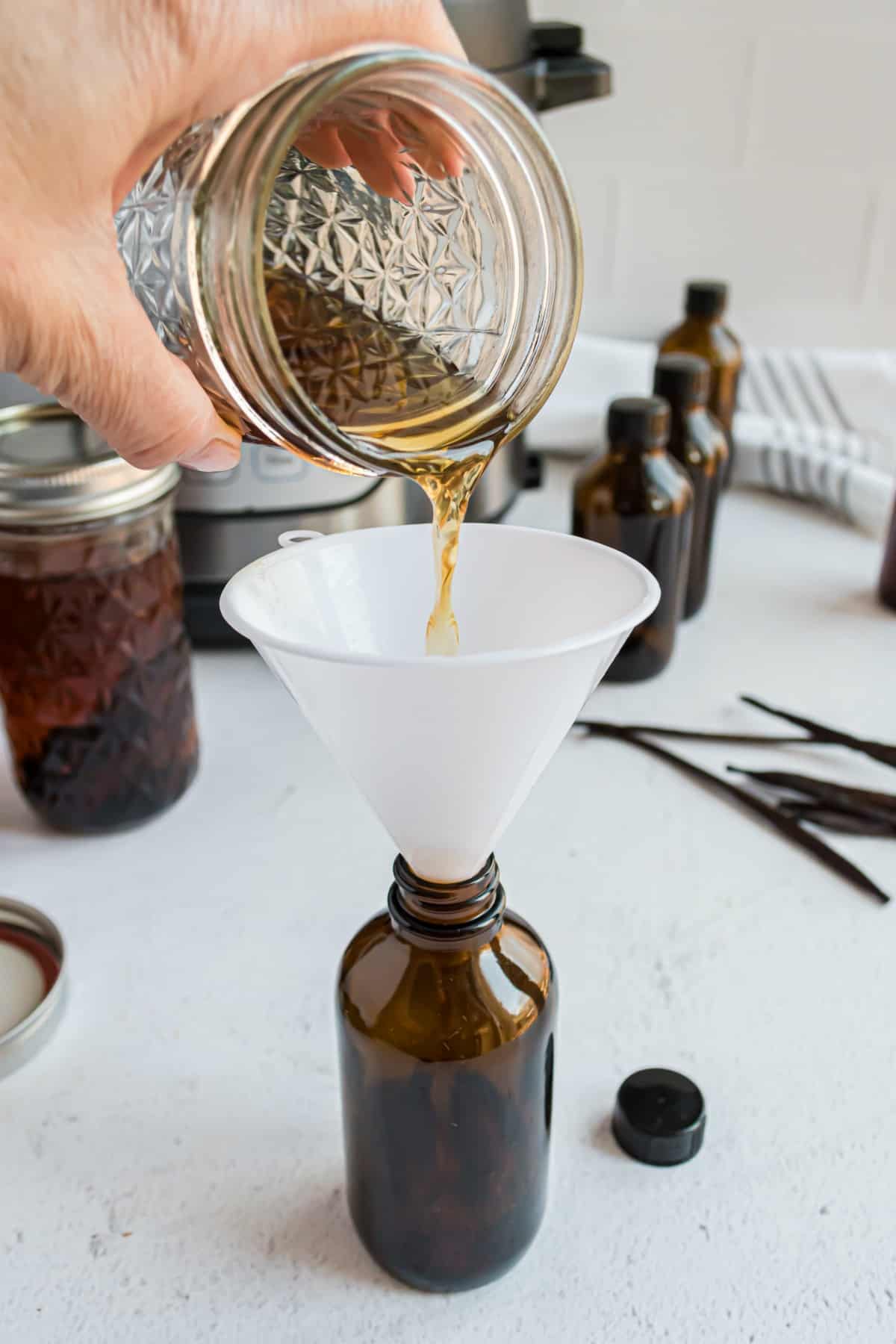 Pouring homemade vanilla extract into glass bottles.