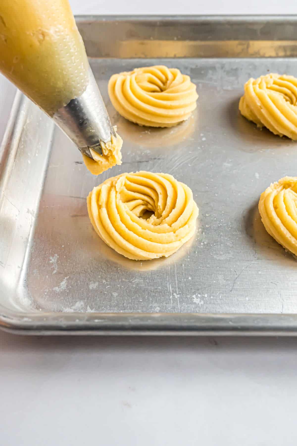 Butter cookies piped onto baking sheet.