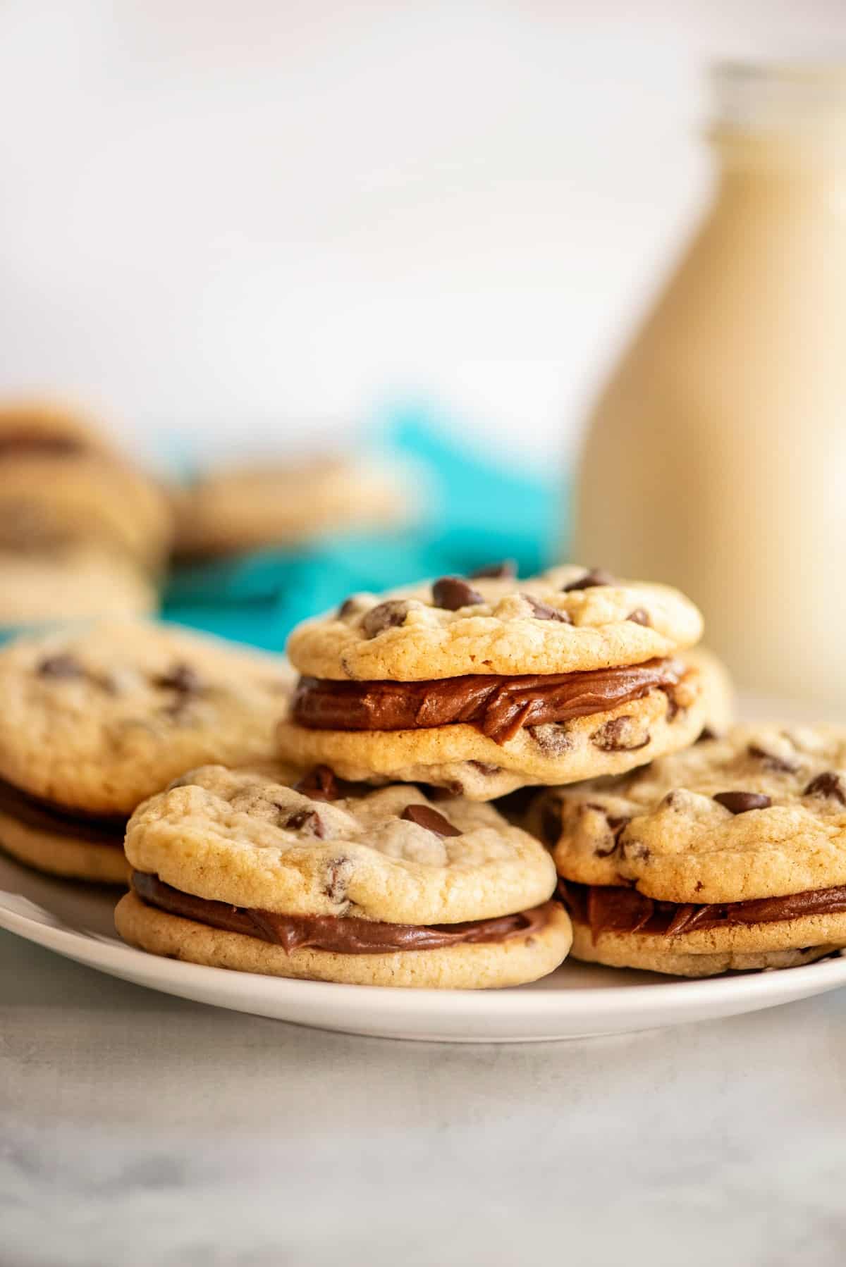 Chocolate Chip cookie sandwiches stacked on a white plate.