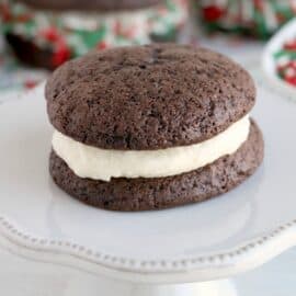 Chocolate whoopie pie with cream filling on small cake stand.