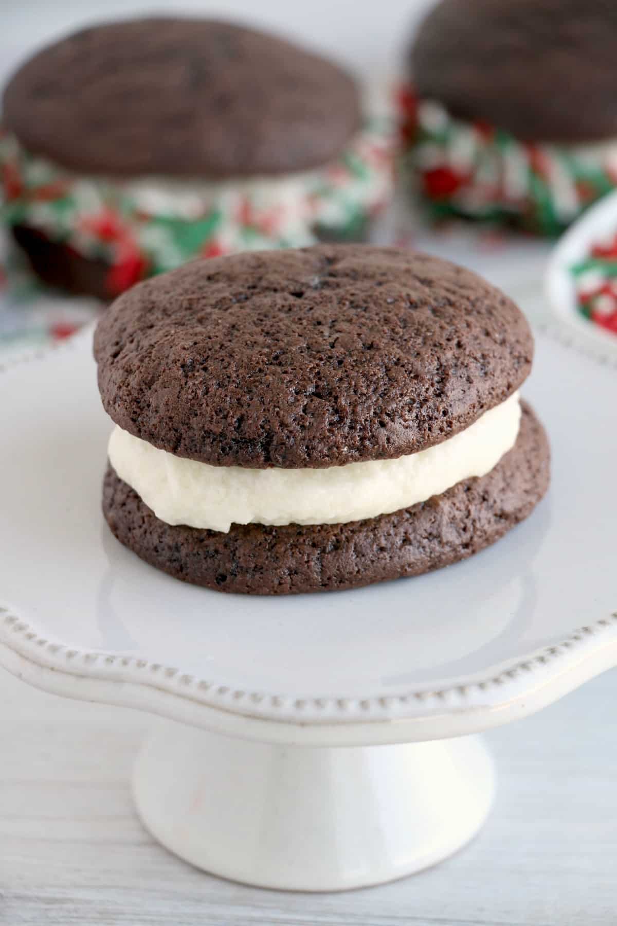 Chocolate whoopie pie with cream filling on small cake stand.