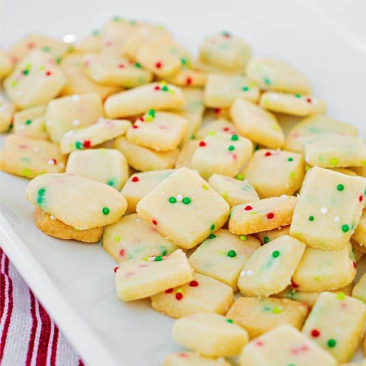 Christmas shortbread cookie bites on white plate.